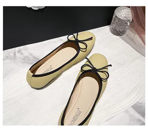 Top view of yellow litchi grain leather ballet flats with black bow and soft sole
