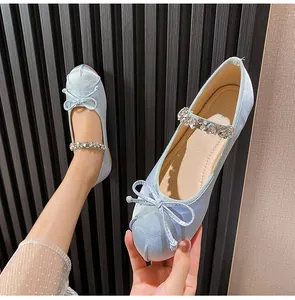 Close-up of light blue satin ballet flat with sparkling rhinestone strap and bow detail