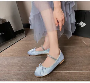 Detail of light blue satin ballet flats featuring a rhinestone strap and bow detail