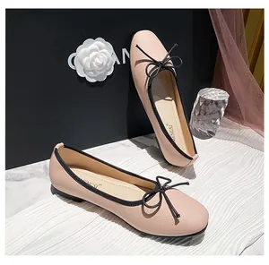 Close-up of pink leather ballet flats with black bow detail and contrasting trim