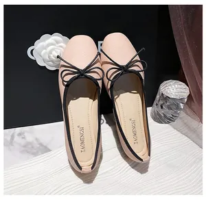 Close-up of pink leather ballet flats with a black bow on a luxury gift box