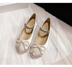 Top view of white satin Mary Jane flats with bow detail and rhinestone straps