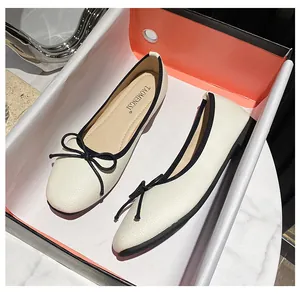 Top view of cream ballet flats with black bow detail and textured leather finish
