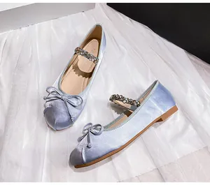Detail of light blue satin ballet flat with rhinestone strap and bow decoration