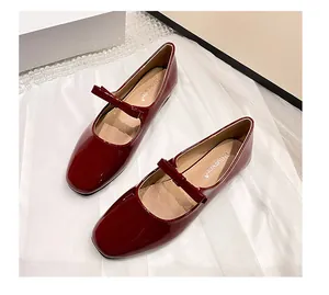 Détail de ballerines Mary Jane en cuir verni rouge avec bride à nœud sur fond blanc