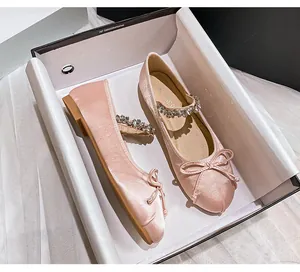 Detail view of pink satin Mary Jane ballet flats with rhinestone strap in a gift box