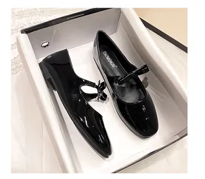 Vue de dessus des ballerines Mary Jane en cuir verni noir brillant avec nœud dans leur boîte