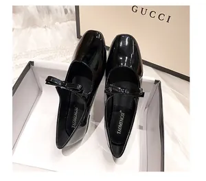 Détail de ballerine Mary Jane en cuir verni noir avec nœud et finition brillante