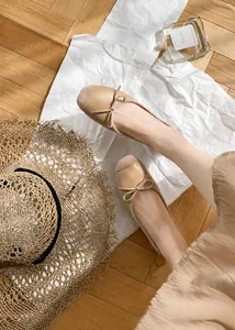 Vista dall'alto di eleganti ballerine a punta quadrata con fiocco in similpelle beige