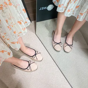 Beige ballet flats with black trim and delicate bow knot shown on a floral dress model