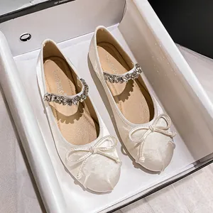 Cream satin ballet flats with rhinestone strap and bow detail in a shoe box