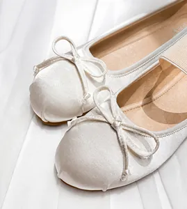 Detail view of round toe ballet flats featuring silk satin fabric and a delicate bow tie