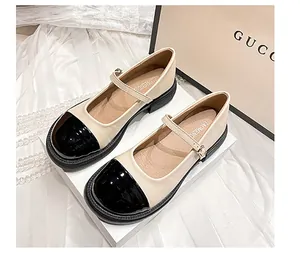 Detail van beige en zwarte Mary Jane-schoenen met dikke rubberen zool en zilveren gesp
