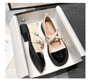 Vue détaillée des chaussures Mary Jane bicolores à double boucle dans leur boîte