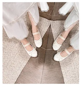 Detailed top view of off-white satin Mary Jane ballet flats with bow and elastic strap