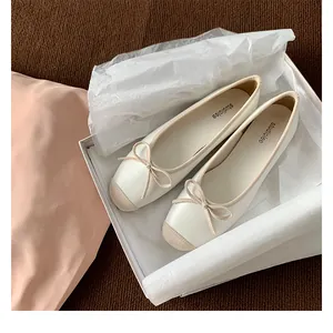 Dettaglio di ballerine stile francese a punta quadrata con fiocco in una confezione regalo