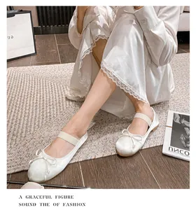 Detail of silk satin ballet flats with bow and elastic strap on wooden floor