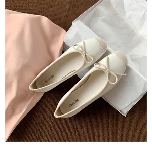 Dettaglio di una ballerina crema con punta in tessuto beige e un delicato fiocco decorativo