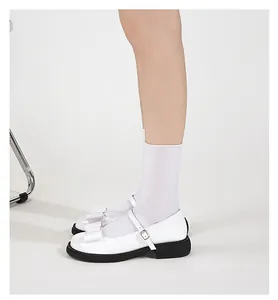 Detail of white patent leather Mary Jane shoes with bow decoration and chunky soles