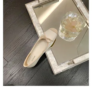 Dettaglio di ballerina beige a punta quadrata con fiocco e finitura in pelle