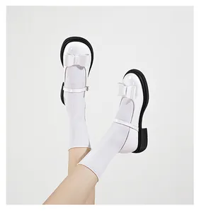 Detail of white patent leather Mary Jane shoes with bow decoration and chunky black soles