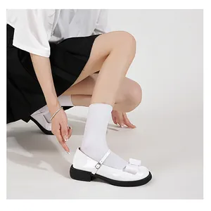 Close-up of white patent leather Mary Jane shoes with bow detail and silver buckle