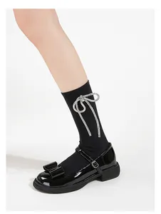 Detail of black patent leather Mary Jane shoes with chunky bow and rhinestone socks