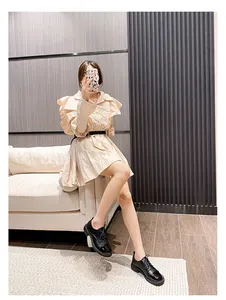 Selfie miroir montrant une robe à volants abricot et des mocassins noirs à lacets vernis