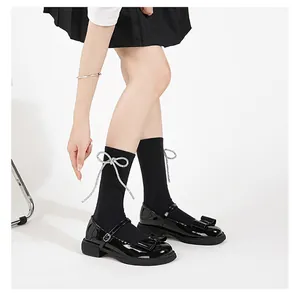 Close-up of black patent leather Mary Jane shoes with bows and sparkly ribbon socks