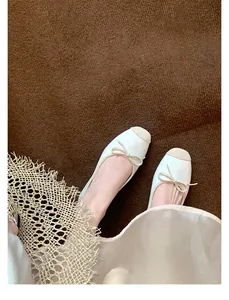Dettaglio di eleganti ballerine bicolore con fiocco e design chic a punta quadrata