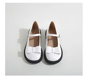 Top view of white patent leather Mary Jane shoes with thick black rubber soles and bows