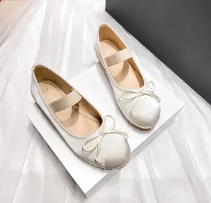Detailed top view of beige satin ballet flats with bow and elastic Mary Jane strap