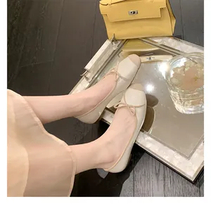 Dettaglio ravvicinato di ballerine beige con punta marrone e fiocco su vassoio a specchio