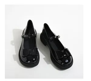 Close-up of black patent leather Mary Jane shoes with bow detail and buckle strap