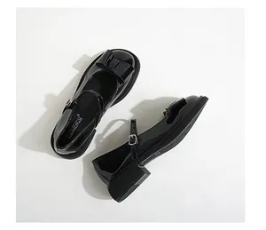Detailed view of black patent leather Mary Jane shoes with bow and non-slip rubber sole