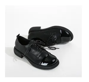 Détail de chaussures Oxford à bout rond en cuir mat et finitions en vernis brillant