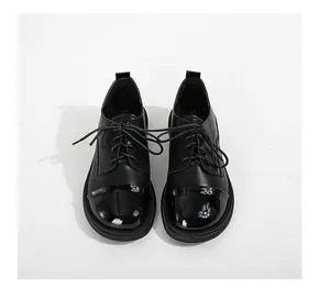 Détail de mocassins à lacets avec un contraste de cuir noir mat et de cuir verni brillant