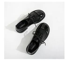 Détail de mocassins en cuir noir avec lacets et bout en cuir verni brillant