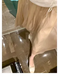 Gonna a pieghe beige stile francese con ballerine bianche su pavimento in marmo
