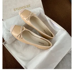 Dettaglio di ballerine beige a punta quadrata con fiocco su uno sfondo materico raffinato