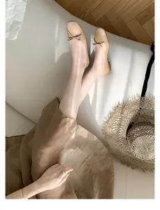 Vista dall'alto di ballerine in pelle beige con fiocco su modella su divano bianco