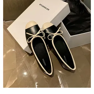 Dettaglio di ballerine francesi con fiocco e punta a contrasto su scatola scarpe