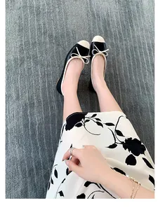 Vista dall'alto di ballerine bicolore con fiocco su un elegante tappeto a righe