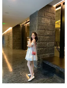 Outfit estivo alla moda con abito bianco a pieghe e borsa a tracolla rosa in pelle
