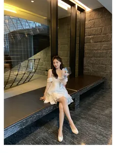 Dettaglio di eleganti ballerine con fiocco e abito estivo bianco a strati sovrapposti