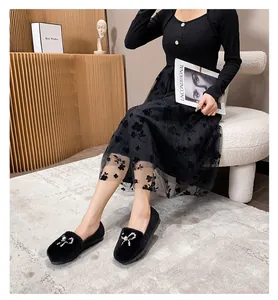 Detail of warm black plush loafers with pearl bow ornament and lace dress styling