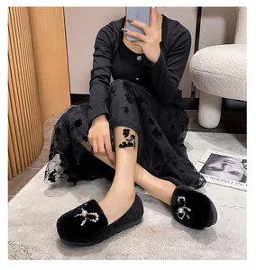 Detail of plush black fur loafers featuring luxury pearl and rhinestone bow buckle