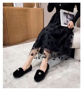 Close-up of black fuzzy loafers with elegant pearl and rhinestone buckle decoration