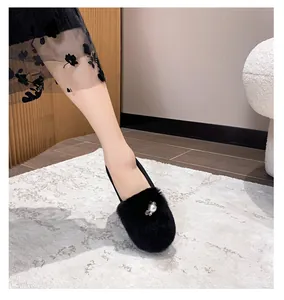 Detail of black plush flat shoe featuring a large pearl and rhinestone accent for winter
