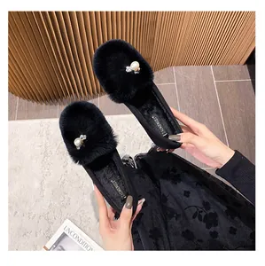 Detail of plush black flat shoes featuring a large faux pearl and sparkling rhinestones